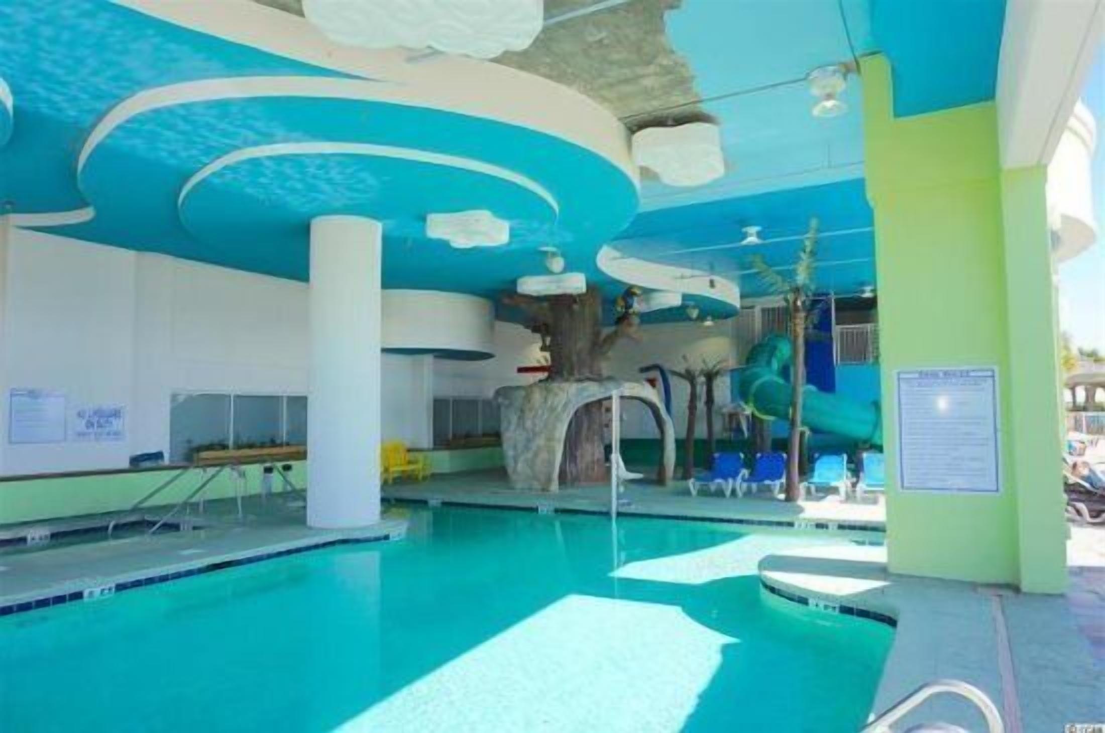 Una piscina interior de diseño moderno, que incluye una estructura de techo singular y un tobogán.