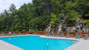 Une piscine rectangulaire dotée d’une terrasse en bois et de chaises longues.
