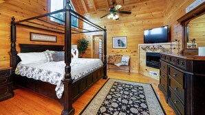 Une chambre située dans un chalet en bois, avec un lit à baldaquin, une télévision et une cheminée.