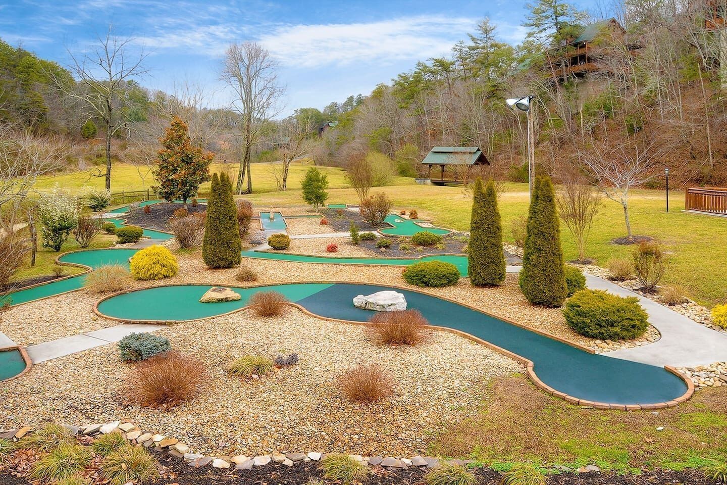 Un parcours de minigolf comportant plusieurs trous, entouré d’espaces aménagés et d’arbres.