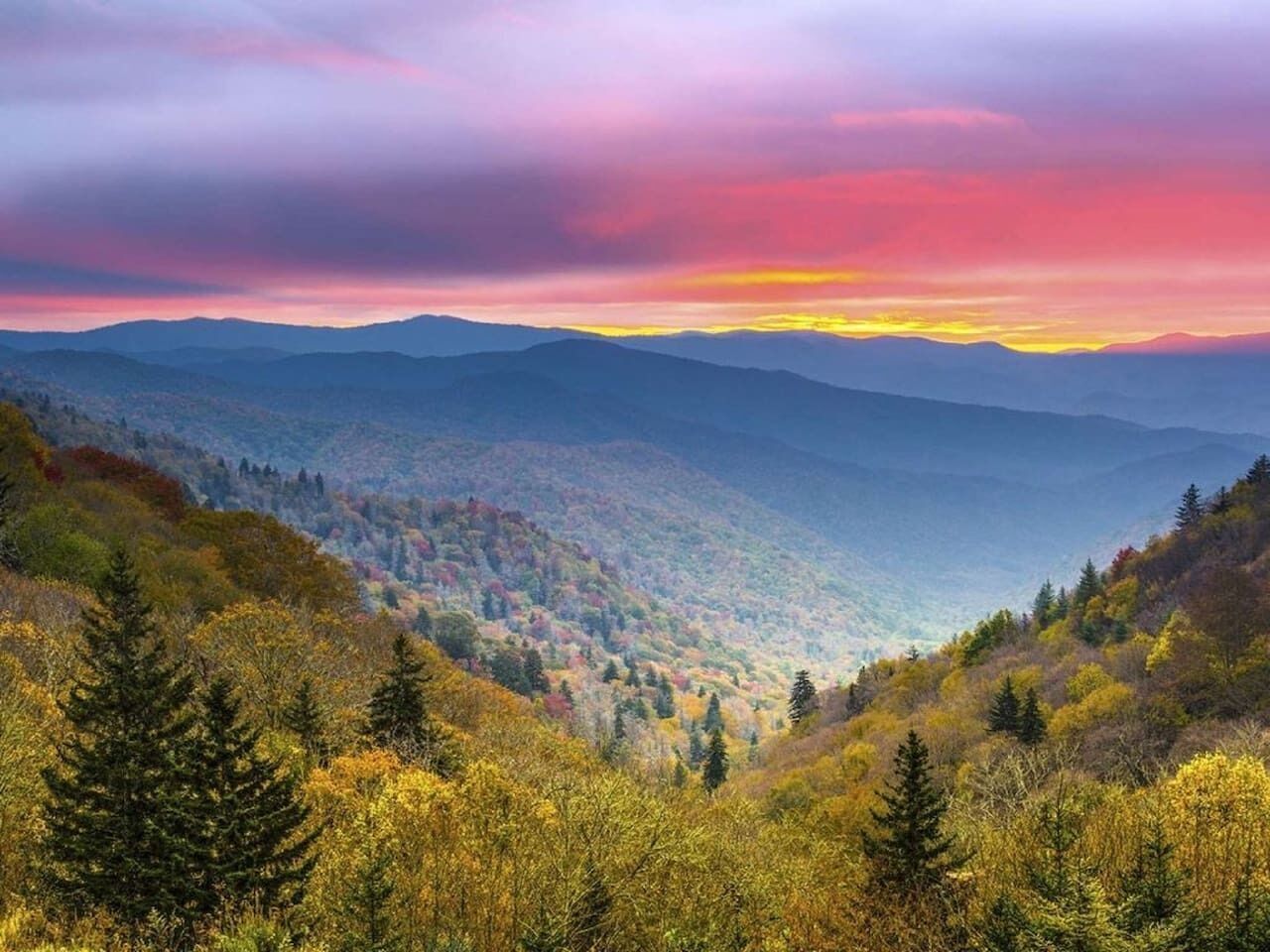 Un paysage montagneux aux couleurs automnales, illuminé par le coucher du soleil.