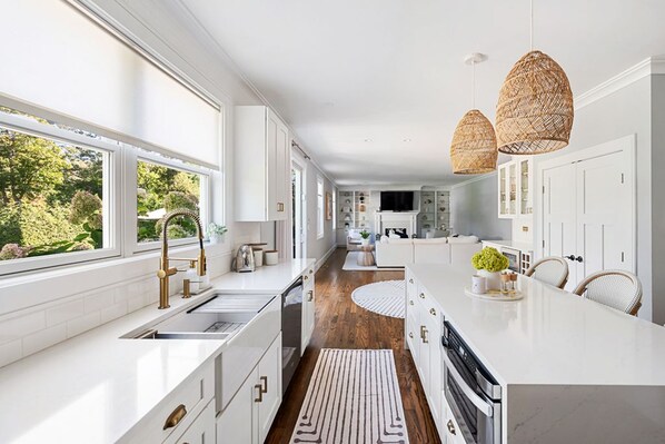 A modern kitchen with white cabinetry, a central island, and a view of the outdoors.