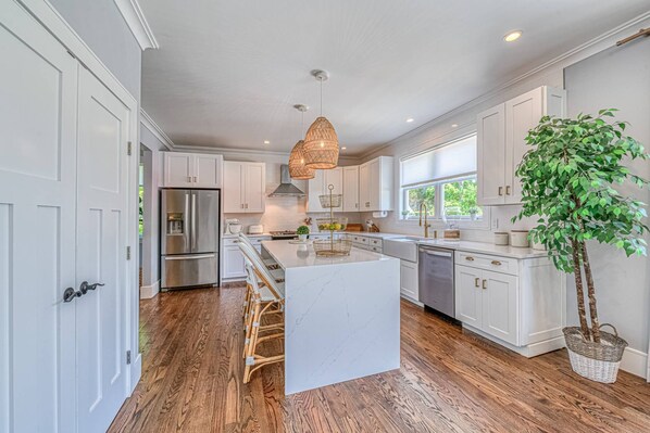 A modern kitchen with white cabinetry, a central island, and a large window.