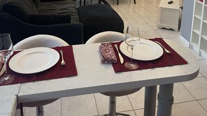 Un comedor con una mesa dispuesta para dos personas, un sofá y una estantería al fondo.