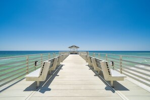 A pier leading to a beach with a small structure at the end.