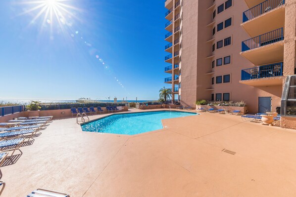 A rooftop pool with sun loungers and a view of the ocean.