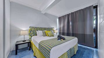 Quarto de hotel com uma cama, mesas de cabeceira e vista por uma cortina.