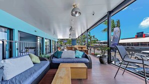 Un espace extérieur moderne aménagé avec un canapé, des fauteuils et une table en bois.