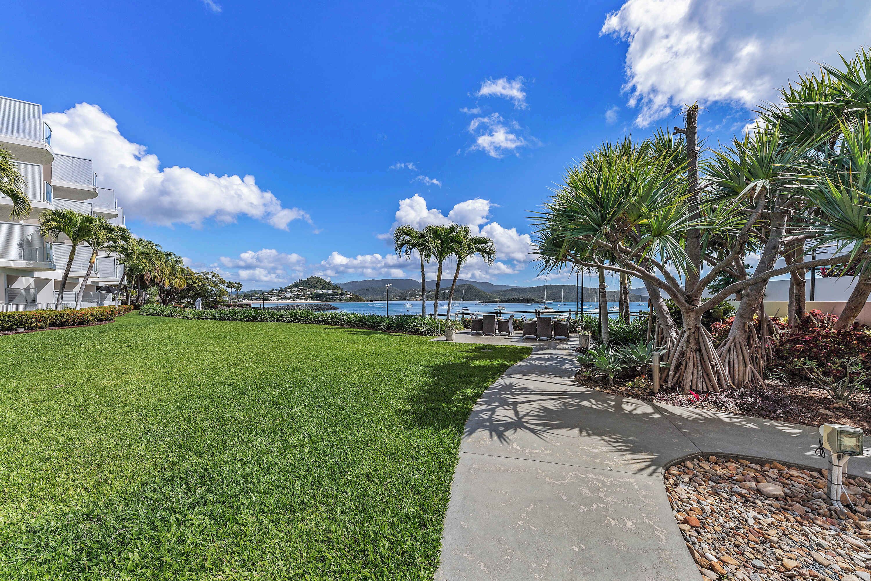 A well-maintained grassy area with a pathway leading to a building with multiple balconies.