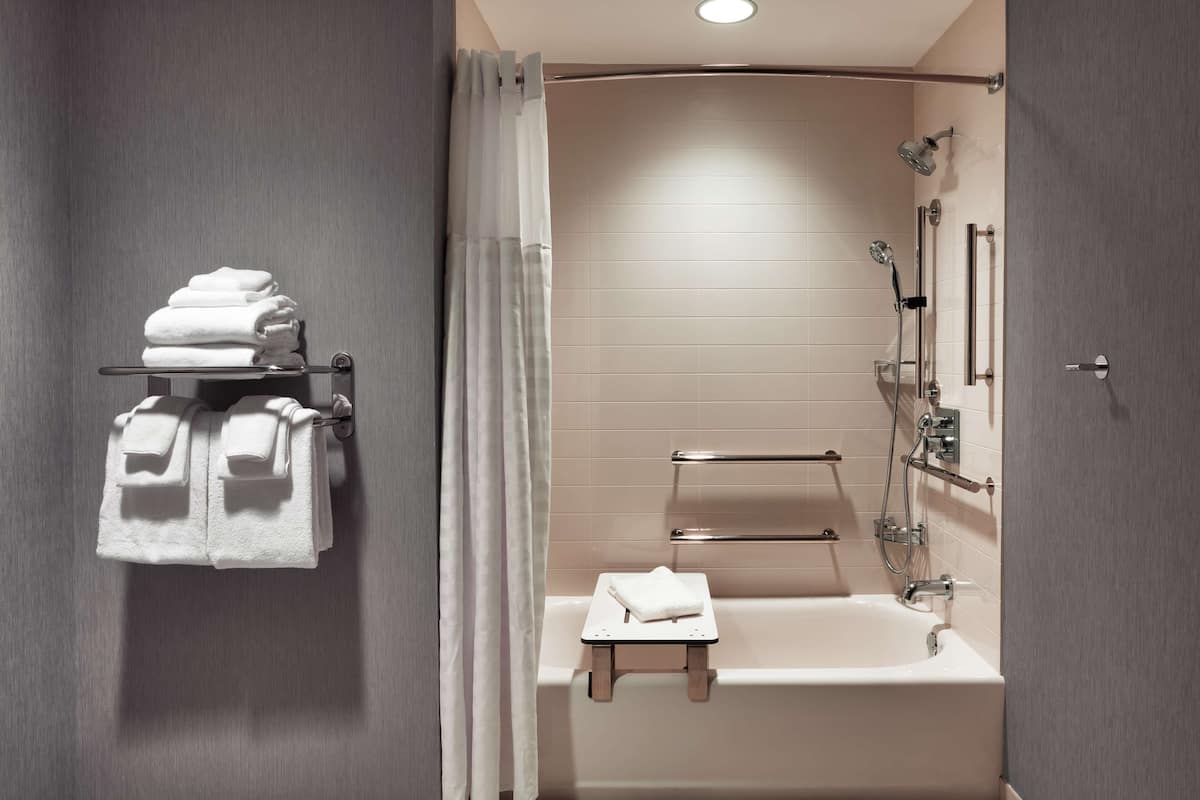 A modern bathroom with a bathtub, shower, and towel rack.