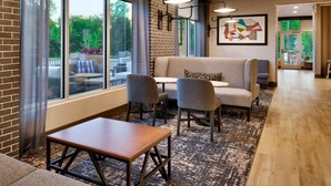 A modern lounge area with a sofa, chairs, a small table, and large windows offering a view of the outdoors. - Hyatt Place Fayetteville/Springdale (Fayetteville)