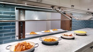 A buffet setup with various dishes and a modern kitchen design. - Hyatt Place Fayetteville/Springdale (Fayetteville)