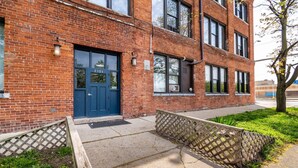 A brick building with a blue door, a small garden area, and a wooden fence. - KING SUITE Loft Downtown 420 friendly - FREE PARKING - FREE Wifi (Detroit)