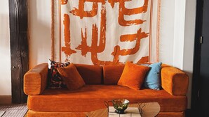 A room with a sofa, a small round table with a bowl, and a tapestry with large orange text on the wall. - KING SUITE Loft Downtown 420 friendly - FREE PARKING - FREE Wifi (Detroit)