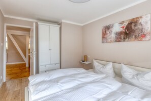 A bedroom with a bed, a wardrobe, a nightstand, and a painting on the wall.