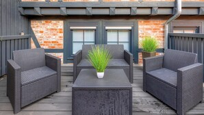 Une terrasse avec des meubles en osier et des plantes en pot.