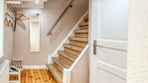 Un escalier avec des marches en bois et une rampe blanche, une porte blanche et un radiateur au sol.