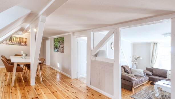 Un vaste espace de vie doté d’un plancher en bois, d’une table à manger avec des chaises, d’un canapé et d’une table basse.