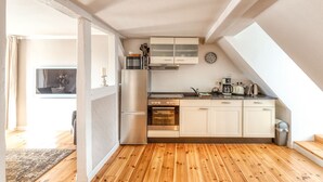 Une cuisine moderne avec un plancher en bois, des armoires blanches, un four encastré et une lucarne.