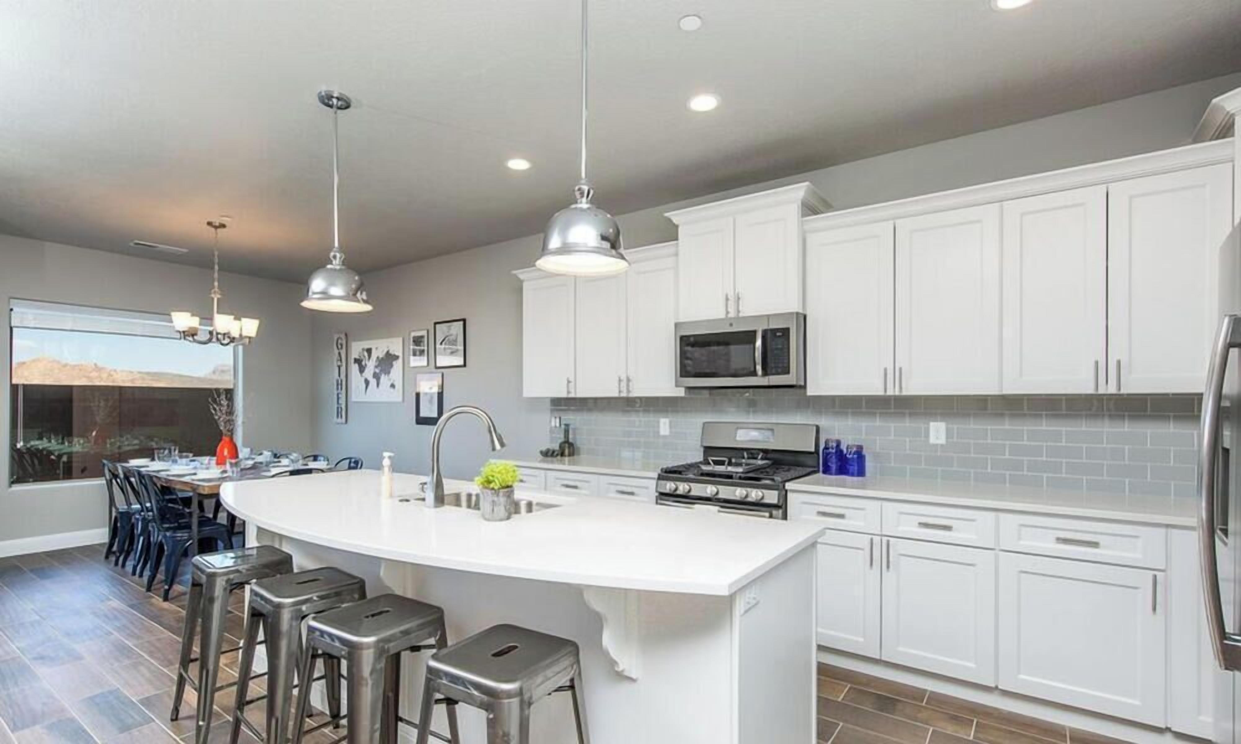 A modern kitchen with white cabinets, stainless steel appliances, and a central island with bar stools.