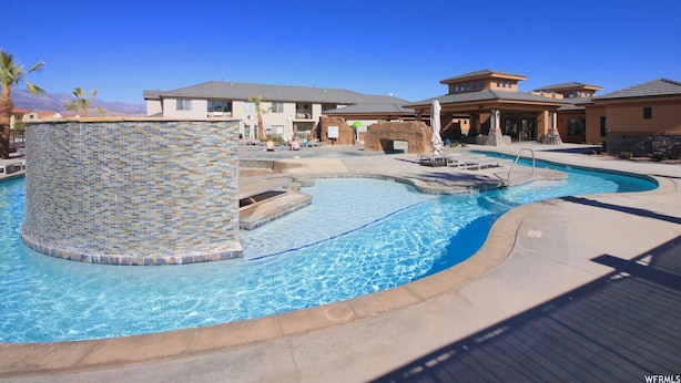 A swimming pool with a mosaic tile wall, lounge chairs, and a view of a resort building. - Southern Utah Vacationing at Its Best! (Hurricane)