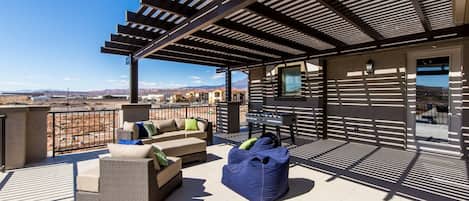 A rooftop patio with outdoor furniture, a foosball table, and a view of the surrounding landscape.
