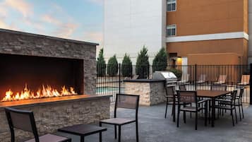 An outdoor patio with a stone wall, a fire feature, and a grill.