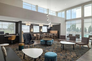 A spacious hotel lobby with a high ceiling, large windows, and a variety of seating options including sofas, chairs, and ottomans. - Residence Inn by Marriott San Marcos (San Marcos)
