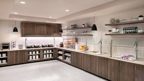 A modern kitchen with wooden cabinets, white tiled backsplash, and glass shelves. - Residence Inn by Marriott San Marcos (San Marcos)