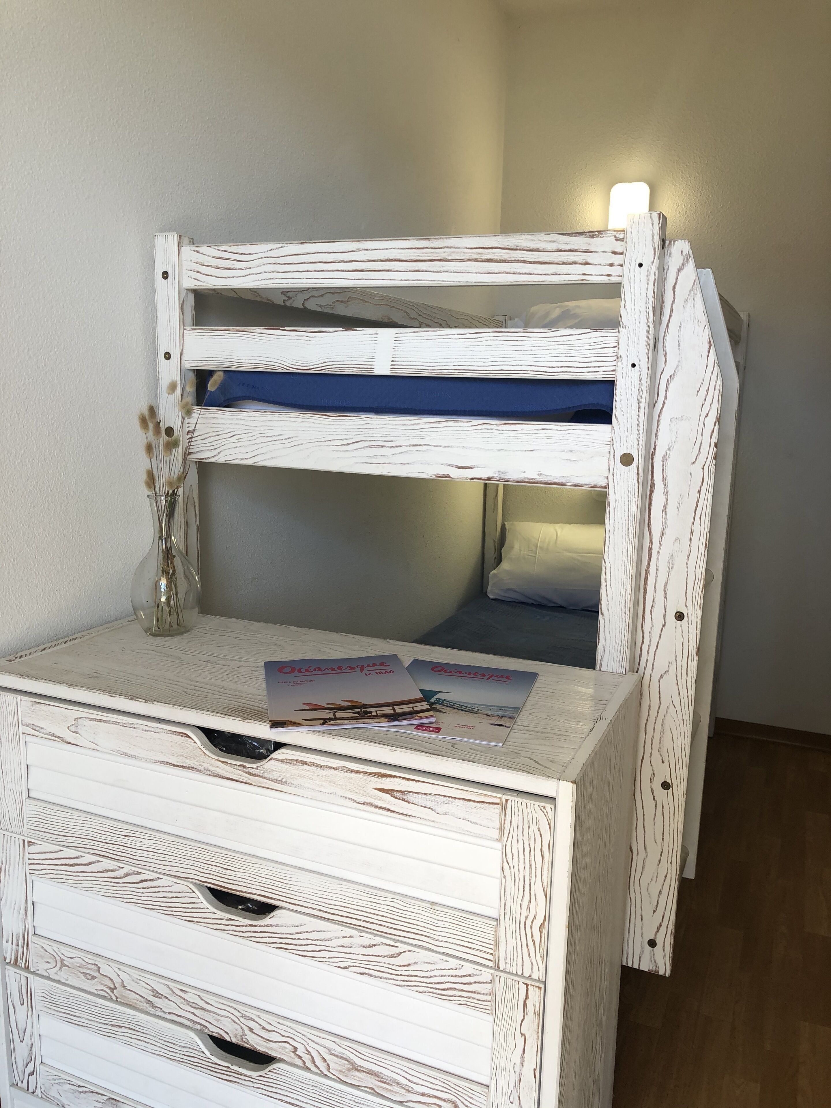 Un lit superposé avec une finition en bois et une petite table devant.