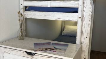 Un lit superposé avec une finition en bois et une petite table devant.