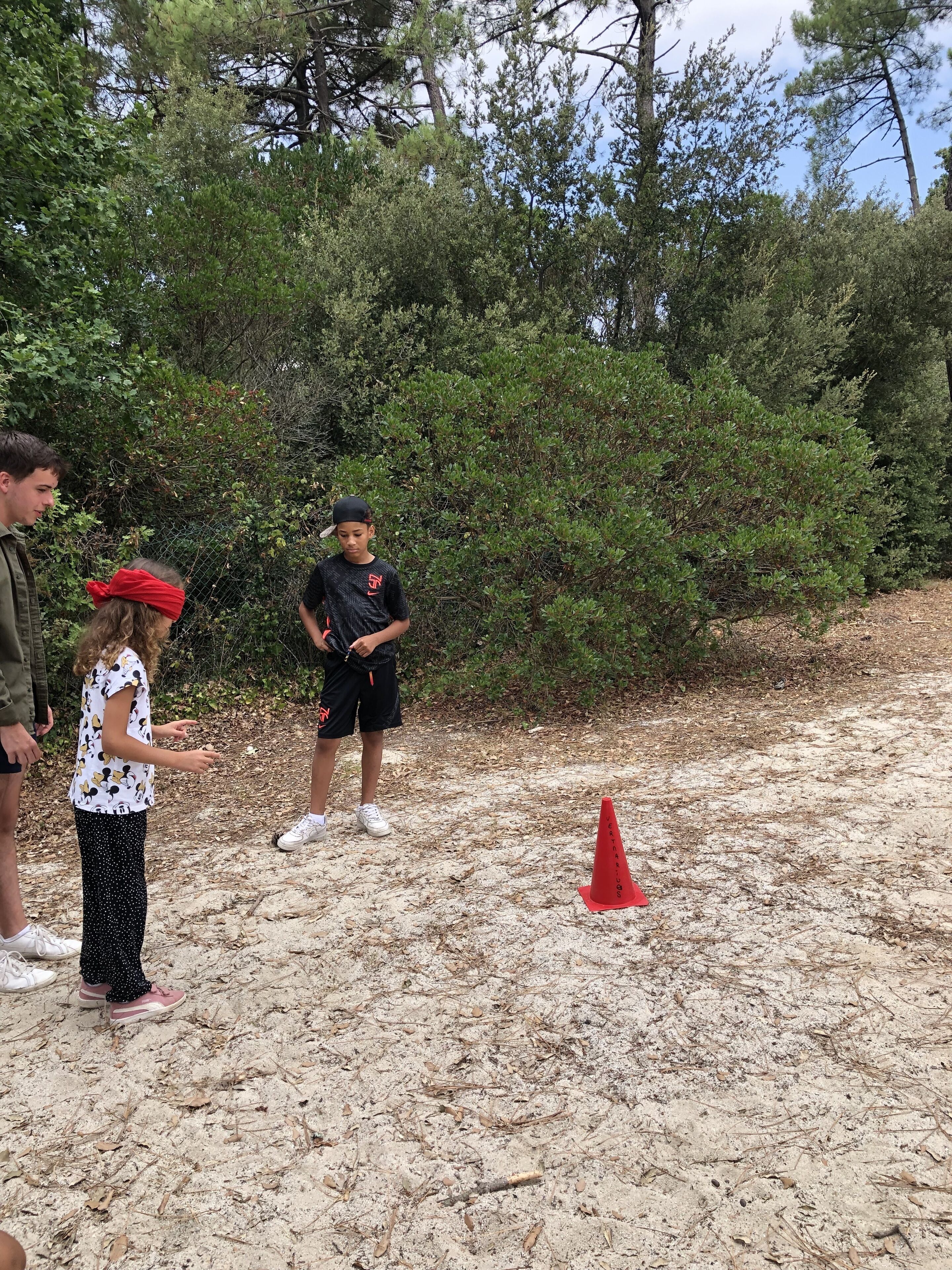 A group of people standing on a sandy path with dense greenery in the background.