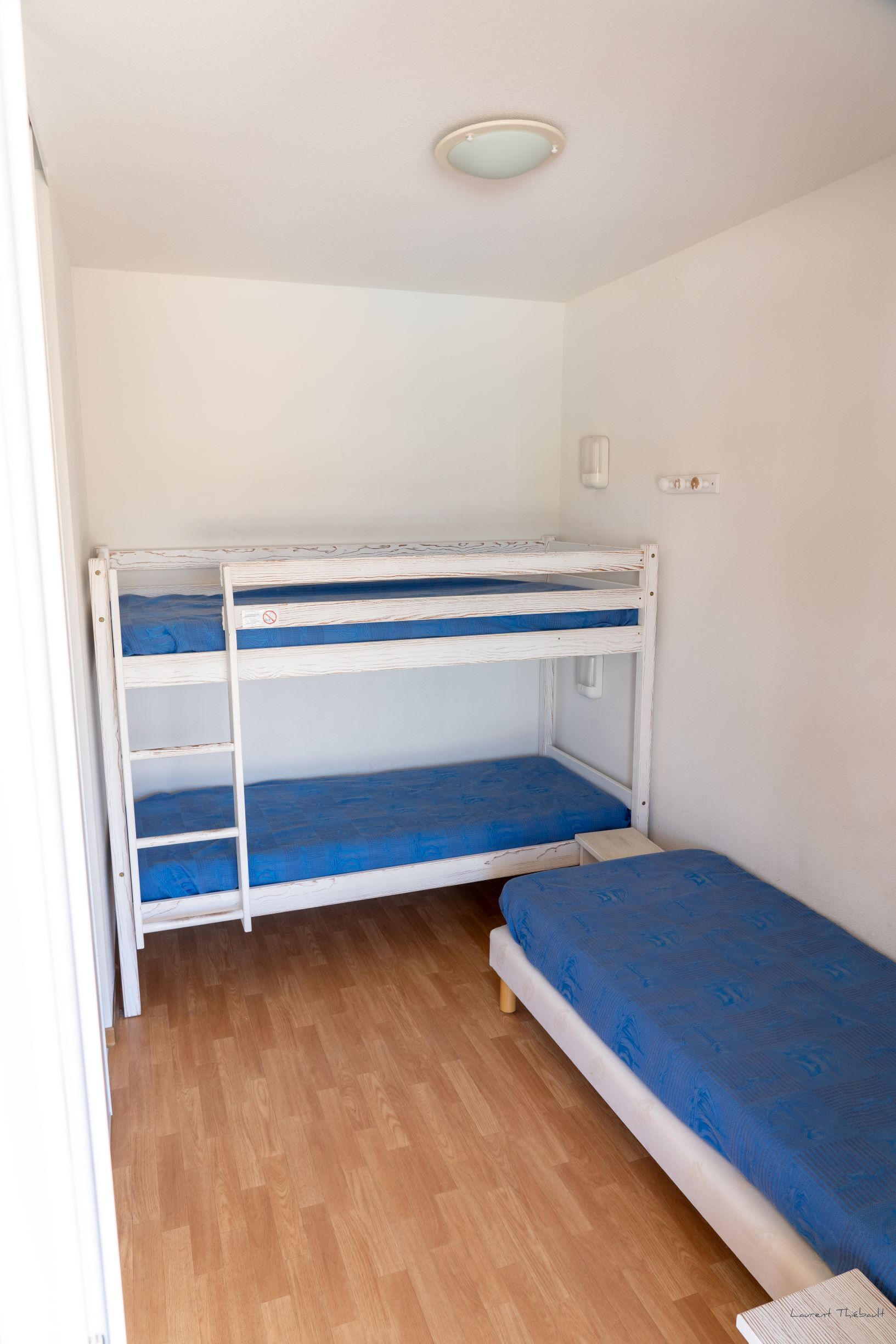 Ein Zimmer mit Etagenbett, Einzelbett und Holzboden.
