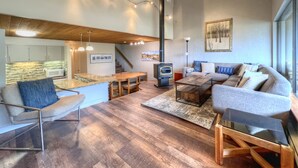 A modern living room with a fireplace, wooden flooring, and a dining area. - Short walk to the slopes, Amazing View with Balcony, Hot Tub! (Mount Crested Butte)