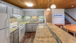 A modern kitchen with granite countertops, white cabinetry, a built-in microwave, and a wooden ceiling. - Short walk to the slopes, Amazing View with Balcony, Hot Tub! (Mount Crested Butte)