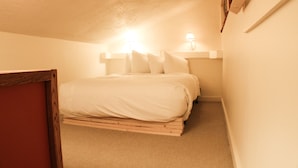 A small, narrow room with a single bed, a nightstand with a lamp, and a wooden headboard. - Short walk to the slopes, Amazing View with Balcony, Hot Tub! (Mount Crested Butte)