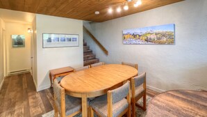 A dining area with a wooden oval table and six chairs, a staircase, and a framed picture on the wall. - Short walk to the slopes, Amazing View with Balcony, Hot Tub! (Mount Crested Butte)