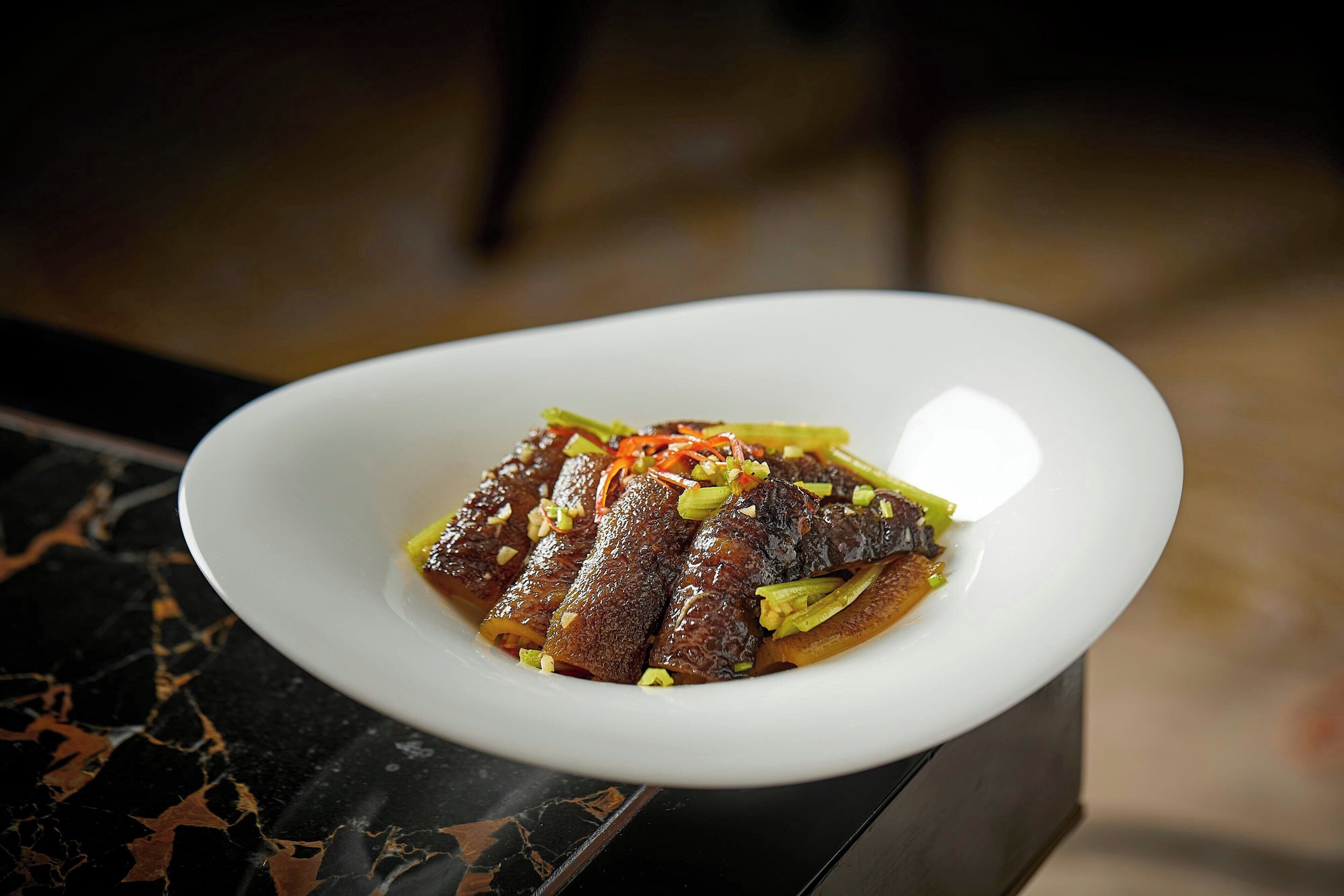 A white plate with a dish of food on a marble surface.
