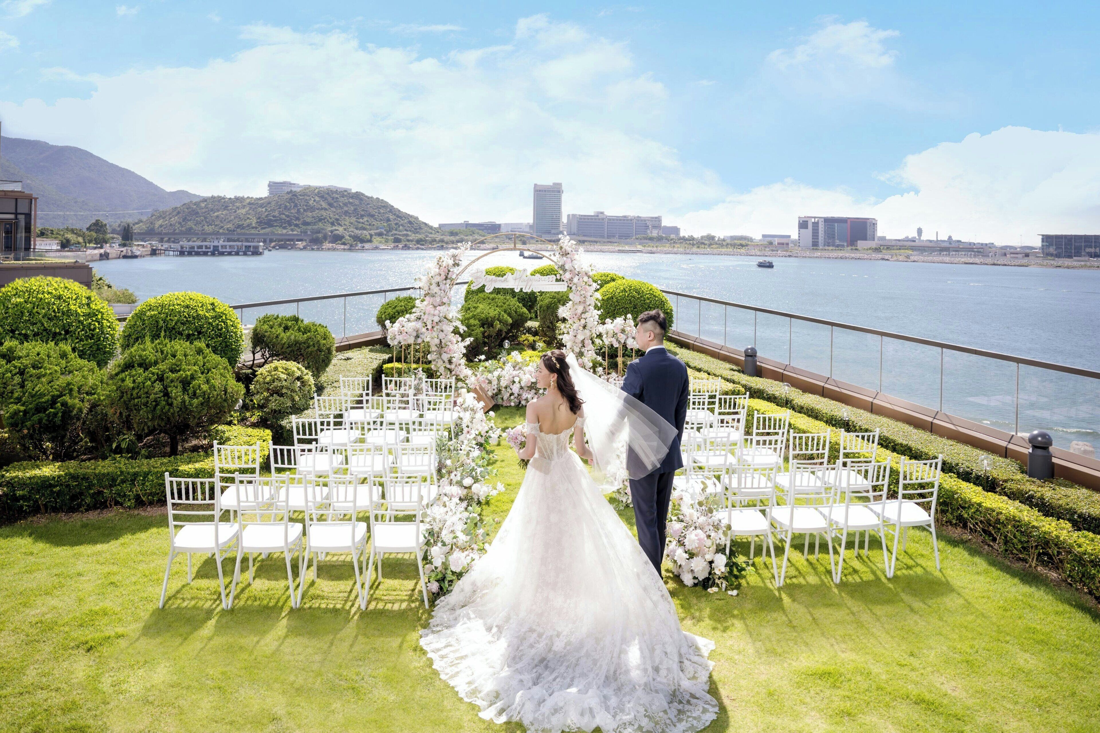A wedding ceremony setup with a view of a body of water and hills in the background.