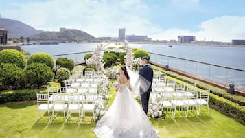 A wedding ceremony setup with a view of a body of water and hills in the background.