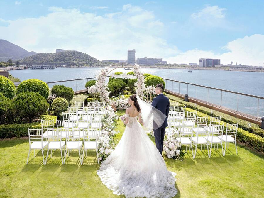 A wedding ceremony setup with a view of a body of water and hills in the background.