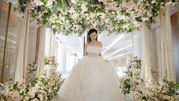Un salón de bodas con una novia en un vestido blanco, rodeada de adornos florales y espejos.