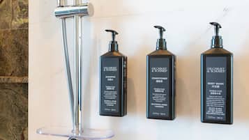 Three Gilchrist & Soames products: shampoo, conditioner, and body wash, mounted on a wall.