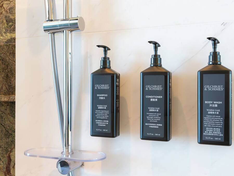 Three Gilchrist & Soames products: shampoo, conditioner, and body wash, mounted on a wall.