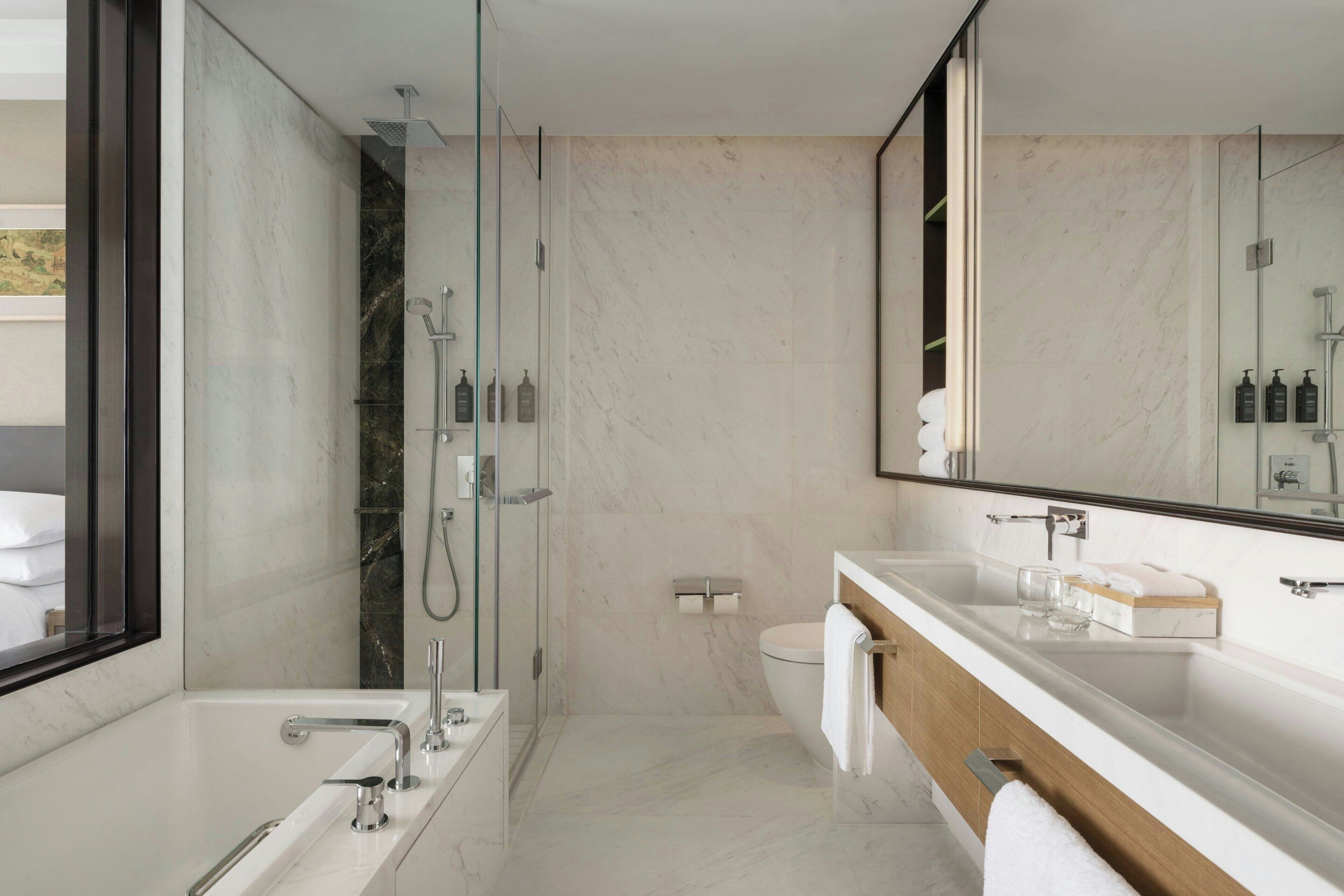 Une salle de bain moderne avec une douche à parois de verre, un grand miroir et un meuble-lavabo en bois.