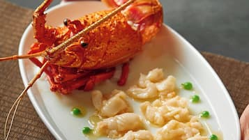 A plate with a cooked lobster tail, dumplings, and peas.