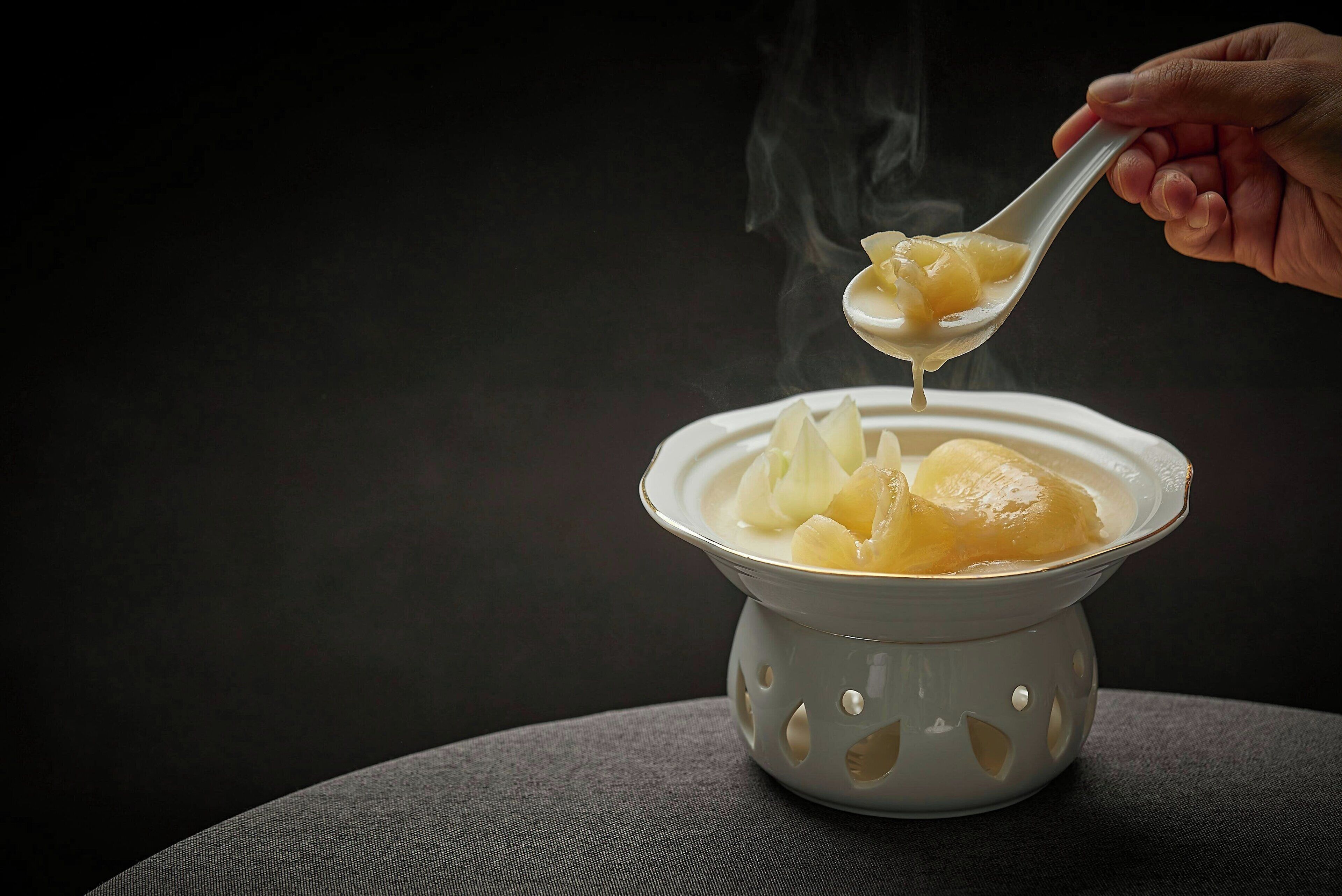 A bowl of food with steam rising from it, placed on a textured surface.