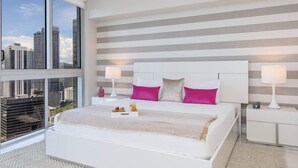 Una habitación de hotel moderna con una cama grande, dos mesitas de noche y vistas a la ciudad.