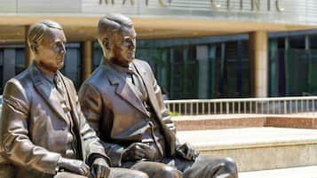A statue of two seated figures in front of a building with 'MAYO CLINIC' signage.