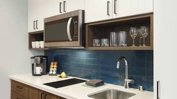 Una cocina moderna con microondas integrado, cafetera y lavabo.
